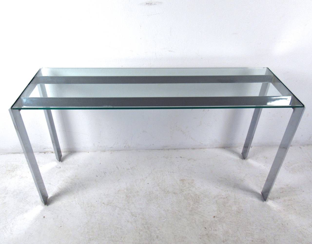 This beautiful console table features a wonderful vintage chrome finish and unique angular  design. Perfect for entry ways, hall use, or as a sofa table for home or office. Please confirm item location (NY or NJ). Pair of side tables available.