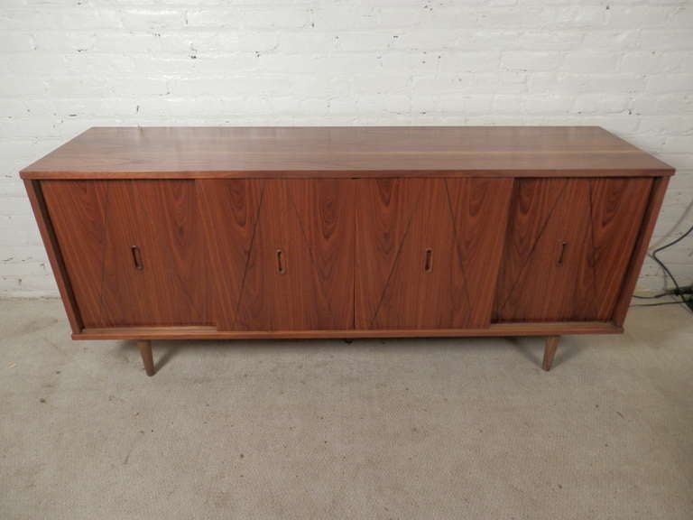 Vintage modern walnut sideboard with four sliding panels that open to storage cabinets. Nice inset door handles, tapered legs and triangle pattern on each panel.

(Please confirm item location - NY or NJ - with dealer)