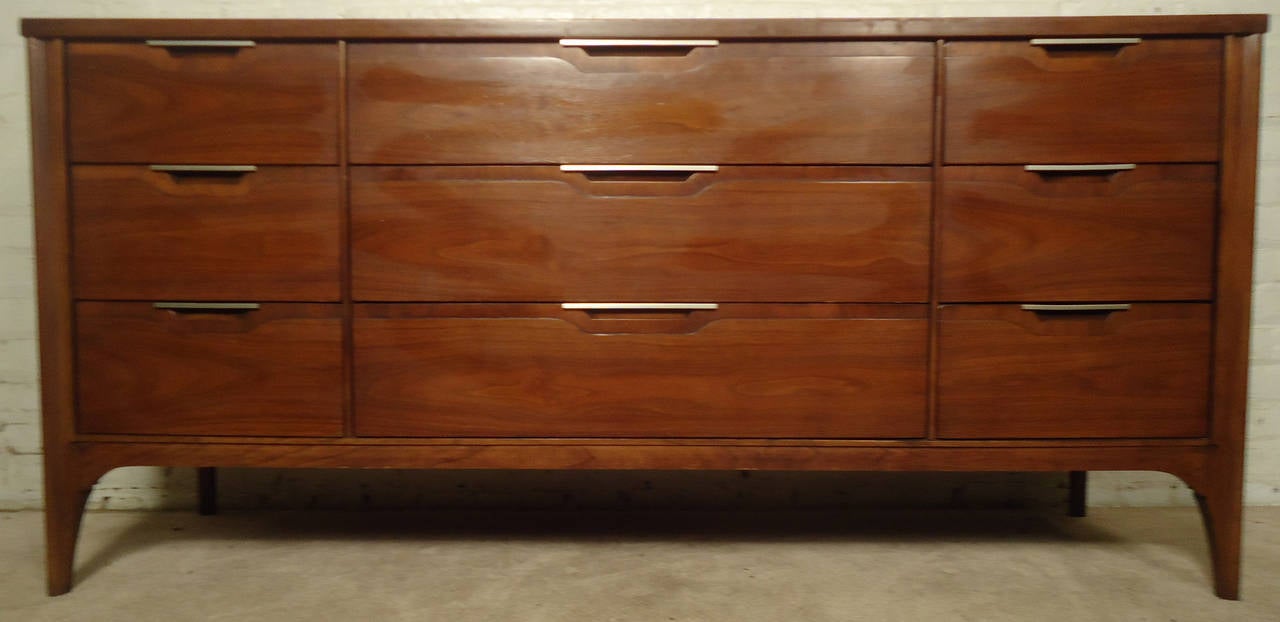Vintage-modern Kent Coffey Impact Series Dresser features beautiful walnut grain and nine drawers with brass pulls.

Please confirm item location NY or NJ with dealer.