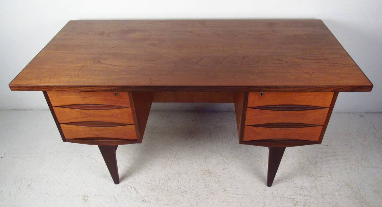 Fantastic double pedestal desk with classic Vodder sculpted drawers, tapered legs, and finished back. Teak grain with rosewood accenting.

(Please confirm item location - NY or NJ - with dealer)