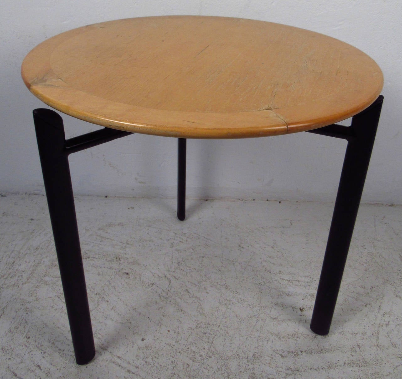 This vintage end table features a sturdy sculpted black metal base with a round maple top. Manufactured by Haworth in Canada, this stylish floating top end table makes a fantastic addition to any seating area. Functional as a side table, end table,