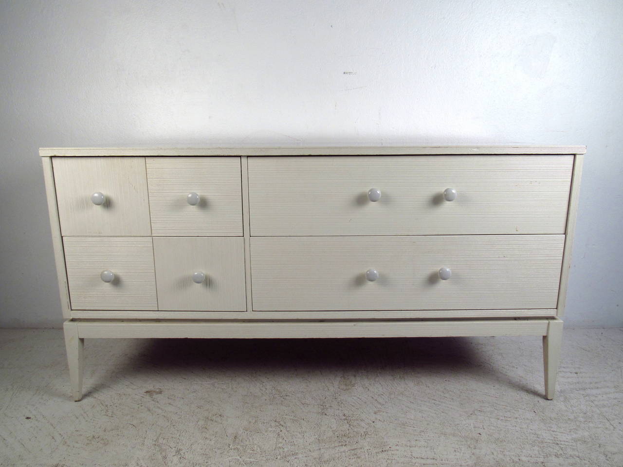 This mid century dresser features a textured white finish, durable laminate top, tapered legs and unique white drawer pulls which offer a modern flare and ample storage to any home or office.

Please confirm item location (NY or NJ) with dealer.