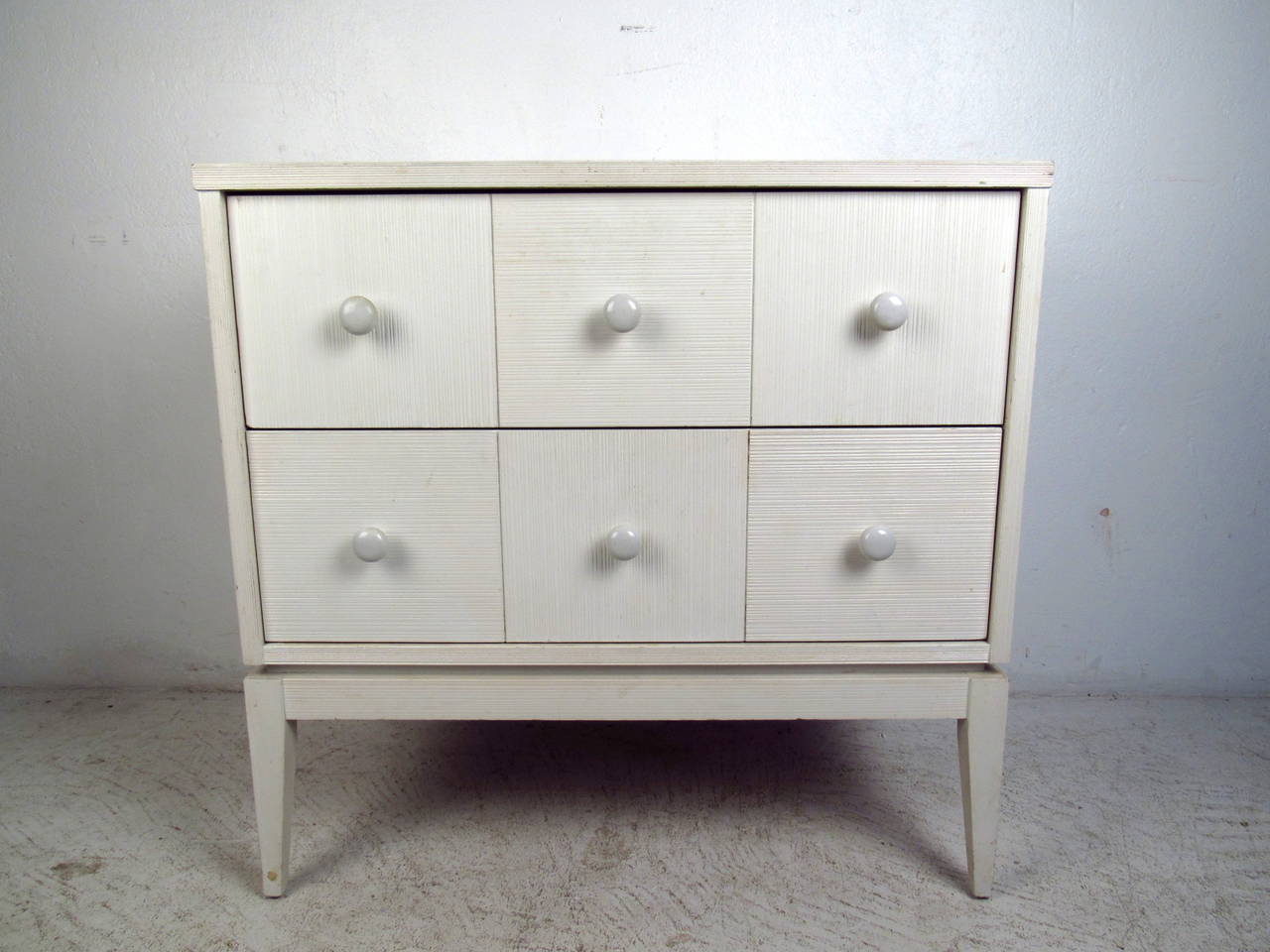 This mid century two drawer chest by Kroehler Furniture features a white textured finish, durable laminate top, and tapered legs which offer ample storage and a subtle modern accent to any home or office.

Please confirm item location (NY or NJ)