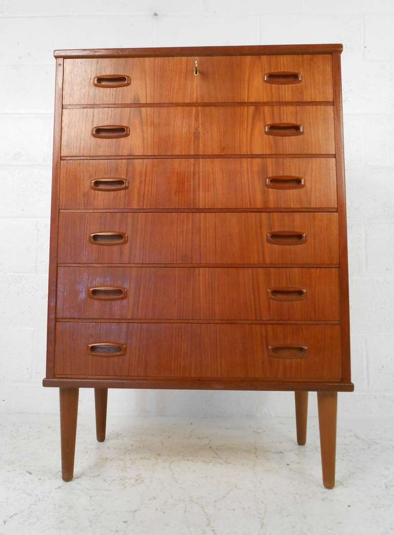 This tall Scandinavian Modern seven drawer dresser makes a stylish Mid-Century Modern addition to home bedroom. Teak finish, carved drawer pulls, and tall tapered legs add to the Danish modern charm of the piece. Please confirm item location (NY or