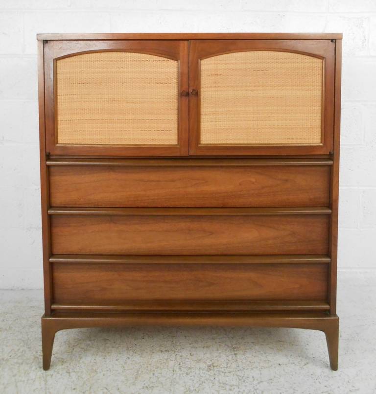 Elegant Mid-Century walnut highboy dresser by Lane Furniture. Featuring reversible cane or walnut cabinet doors, which conceal two additional drawers. American walnut finish makes a retro vintage modern addition to any interior. Please confirm item