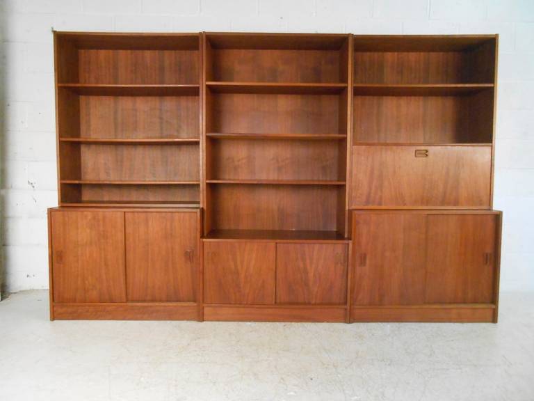 This large six piece wall unit combines mid-century style and storage, and makes an impressive statement in any setting. Drop down desk includes working lighting. Rich Danish Teak, unique carved handles, adjustable shelves, and plenty of display