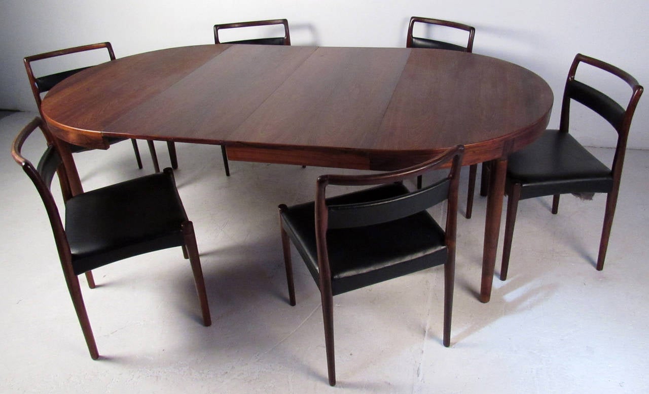Vintage Danish dining set, includes one rosewood dining table with two leaves and six leather upholstered dining chairs, beautiful wood grain and sculpting, designed by Randers Mobelfabrik.

Chair dimensions: 19 W, 17 D, 31 H, 18 SH.

Please confirm