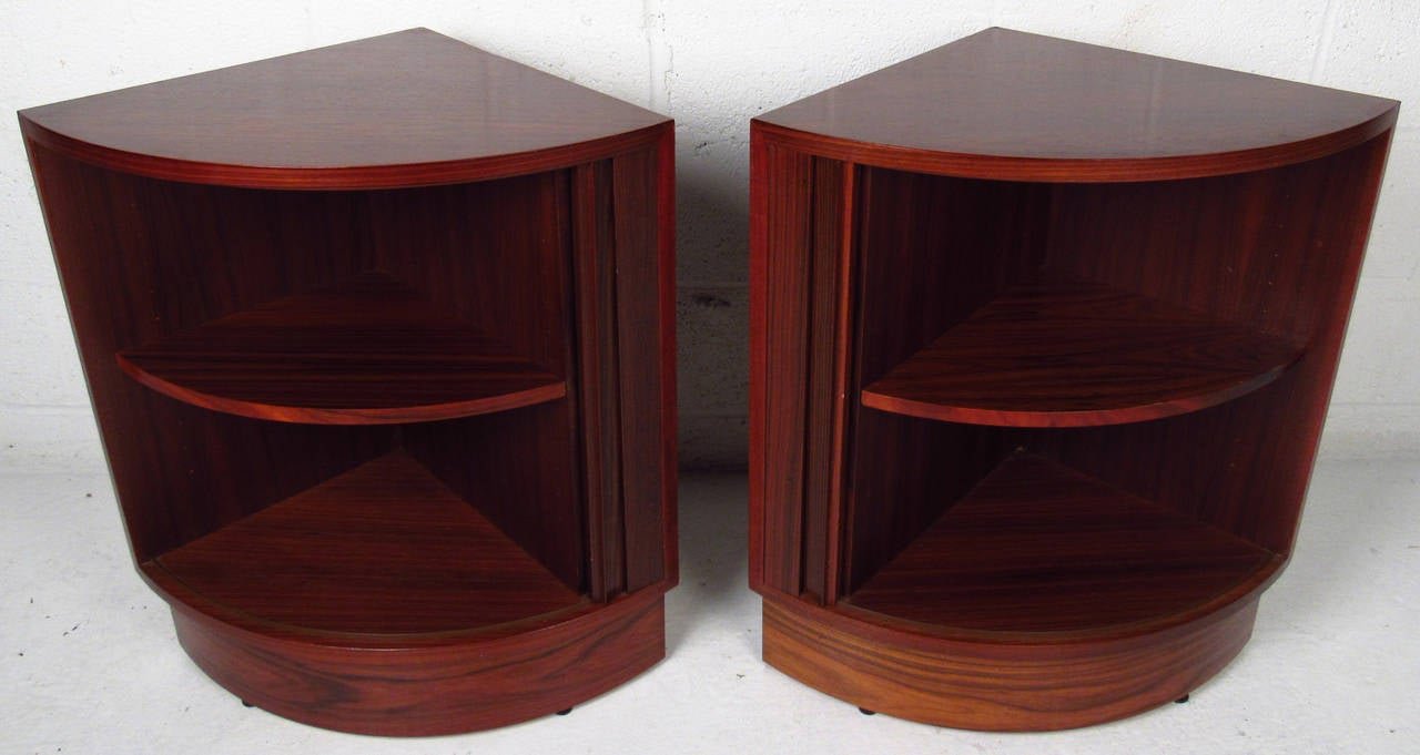Two vintage-modern Danish corner cabinets, features beautiful rosewood grain throughout, tambour doors reveal adjustable interior shelving. Corner cut backs make these a unique finishing touch to bedroom decor or otherwise. 

Please confirm item