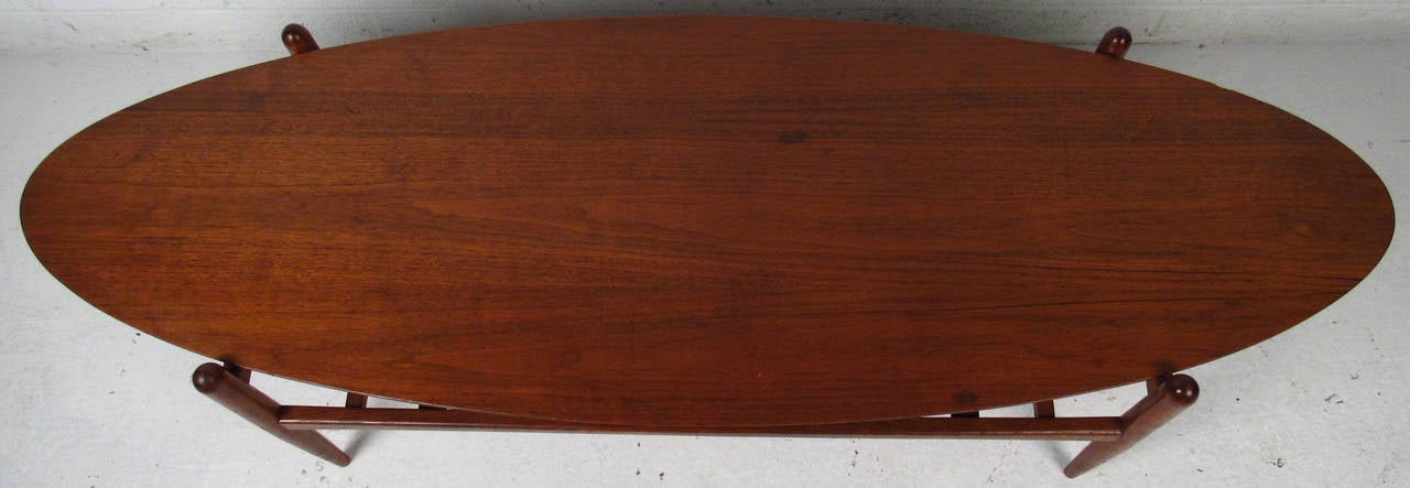 Vintage-modern coffee table, features beautiful natural wood grain, sculpted legs and a woven shelf. Surfboard style oval table top  and quality mid-century construction round out this impressive cocktail table. 

Please confirm item location NY or