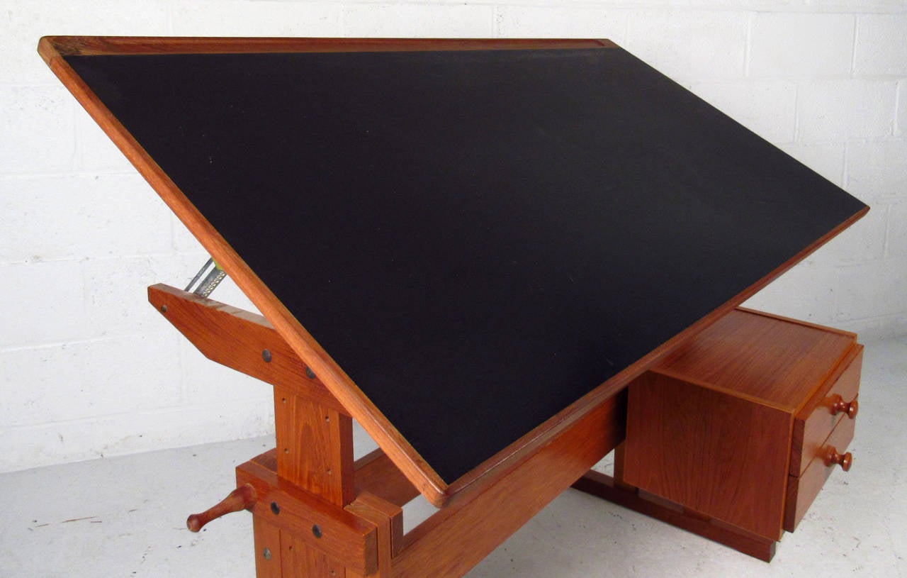 Vintage-modern drafting table from Denmark, features adjustable height and angle, sturdy sled legs, two drawers and beautiful teak grain throughout.

Please confirm item location NY or NJ with dealer.