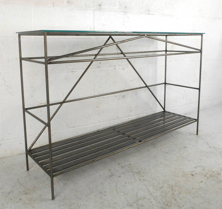 This wonderful modern hall table is made up of a sturdy iron frame with a glass top. Unique lines and a bottom shelf for storage or display make this a useful piece for use as a hall, sofa, or console table. Please confirm item location (NY or NJ).