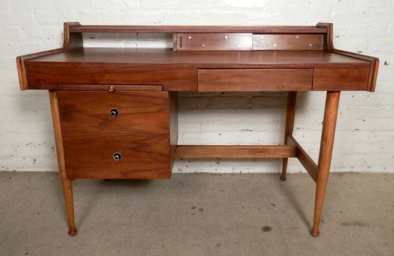 Lovely walnut desk by Hooker for their Mainline series. Three drawers and side work area, sculpted legs, hide-away storage. Beautiful walnut grain and top storage compartment with ivory-like inlays.

Kneehole: 24