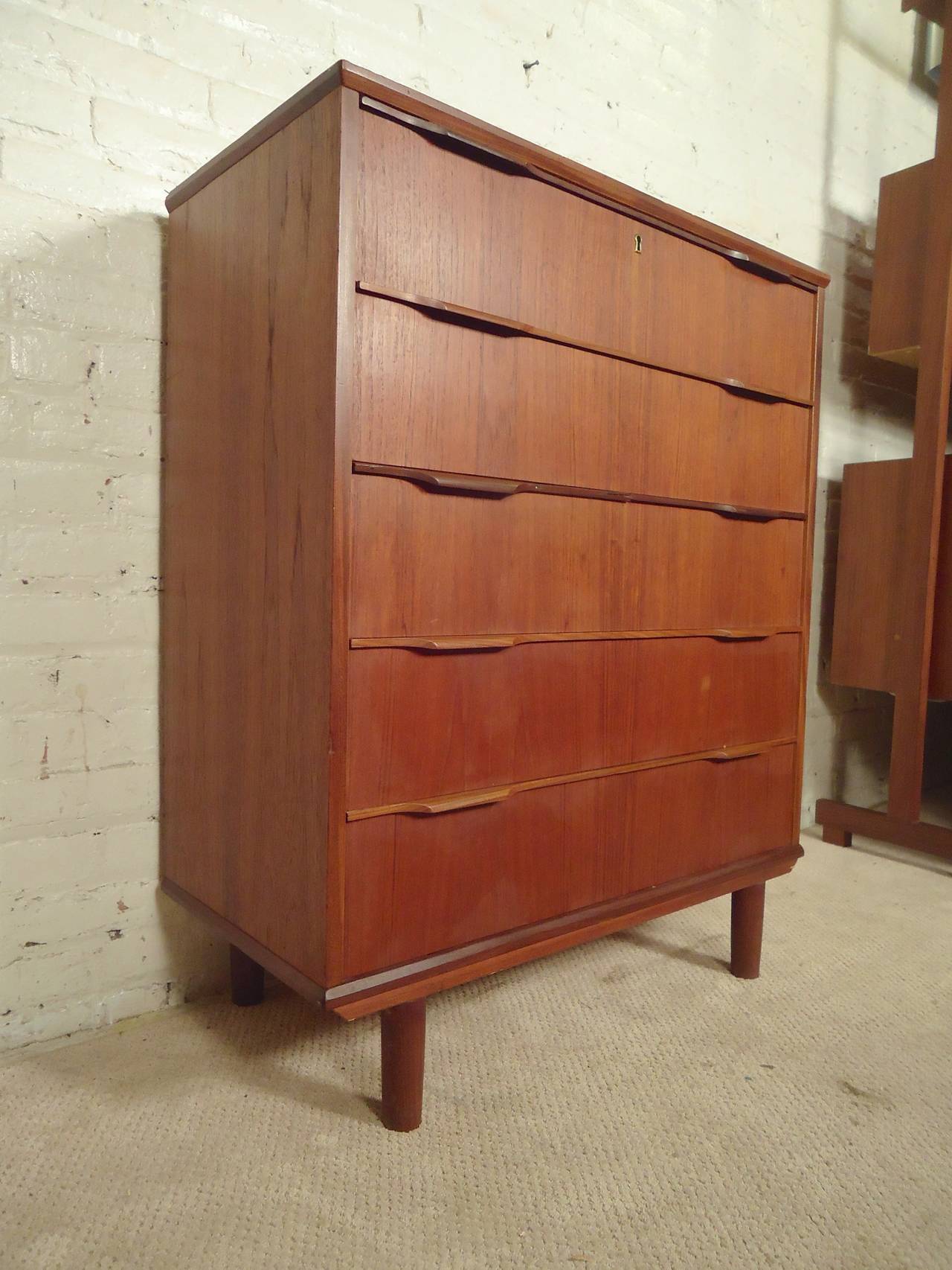 Mid-century modern teak highboy with five sculpted drawers. Simple modern elegance with locking function. 

(Please confirm item location - NY or NJ - with dealer)