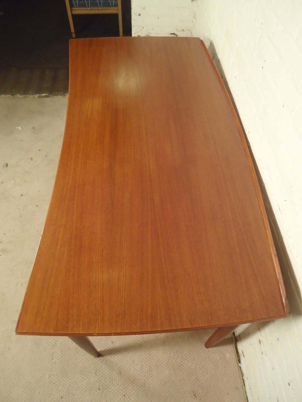 Gorgeous mid-century desk with finished back. Unique curved top with back lip, seven drawers with sculpted handles and tapered legs, with teak grain throughout.
Kneehole: 22w 16d 28h

(Please confirm item location - NY or NJ - with dealer)