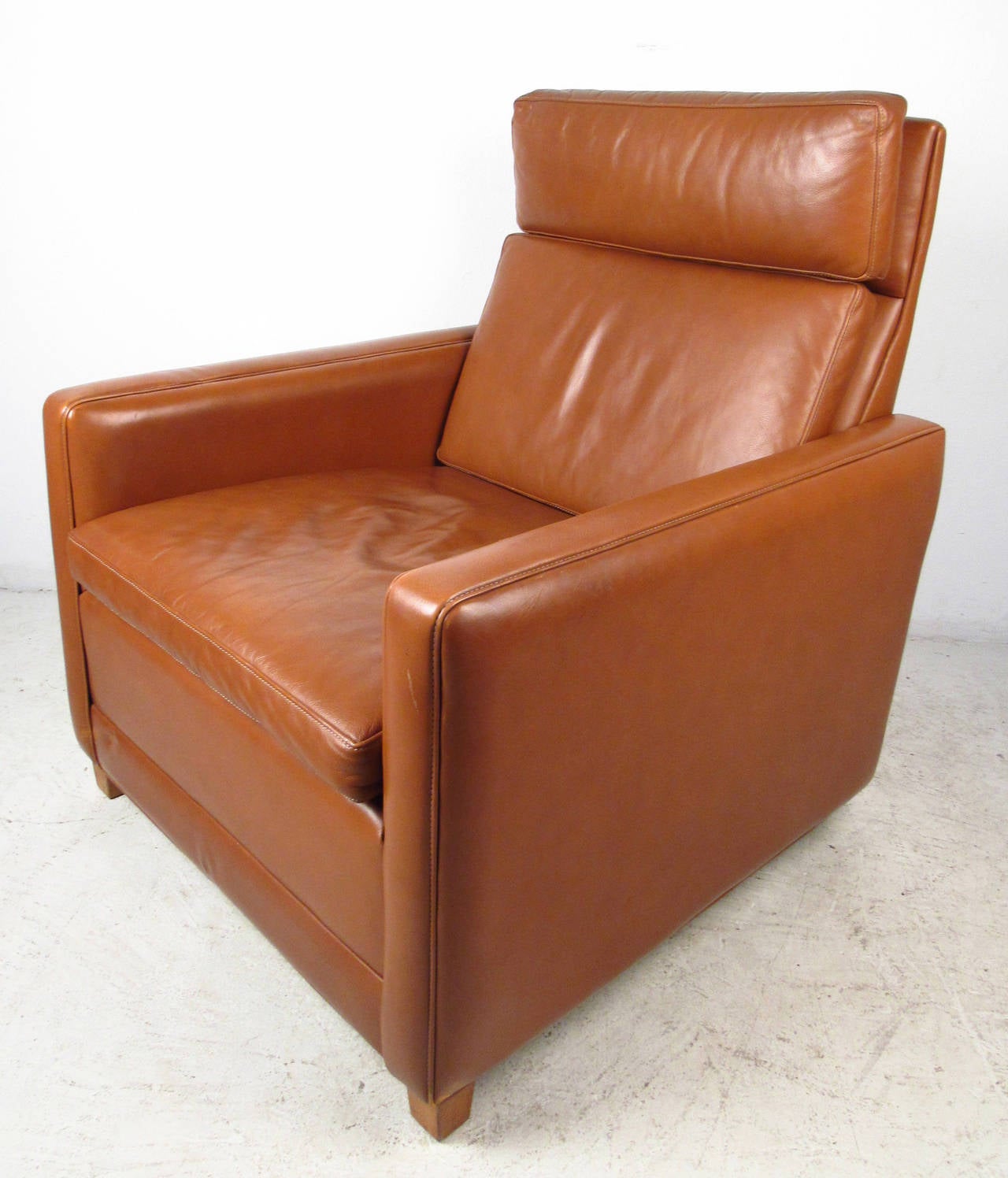 Vintage modern leather lounge chair features a unique design with blonde wood feet in the front and chrome wheels in the back, designed by Børge Mogensen. This unique shape with it's ergonomic seat back makes a comfortable chair for home or business