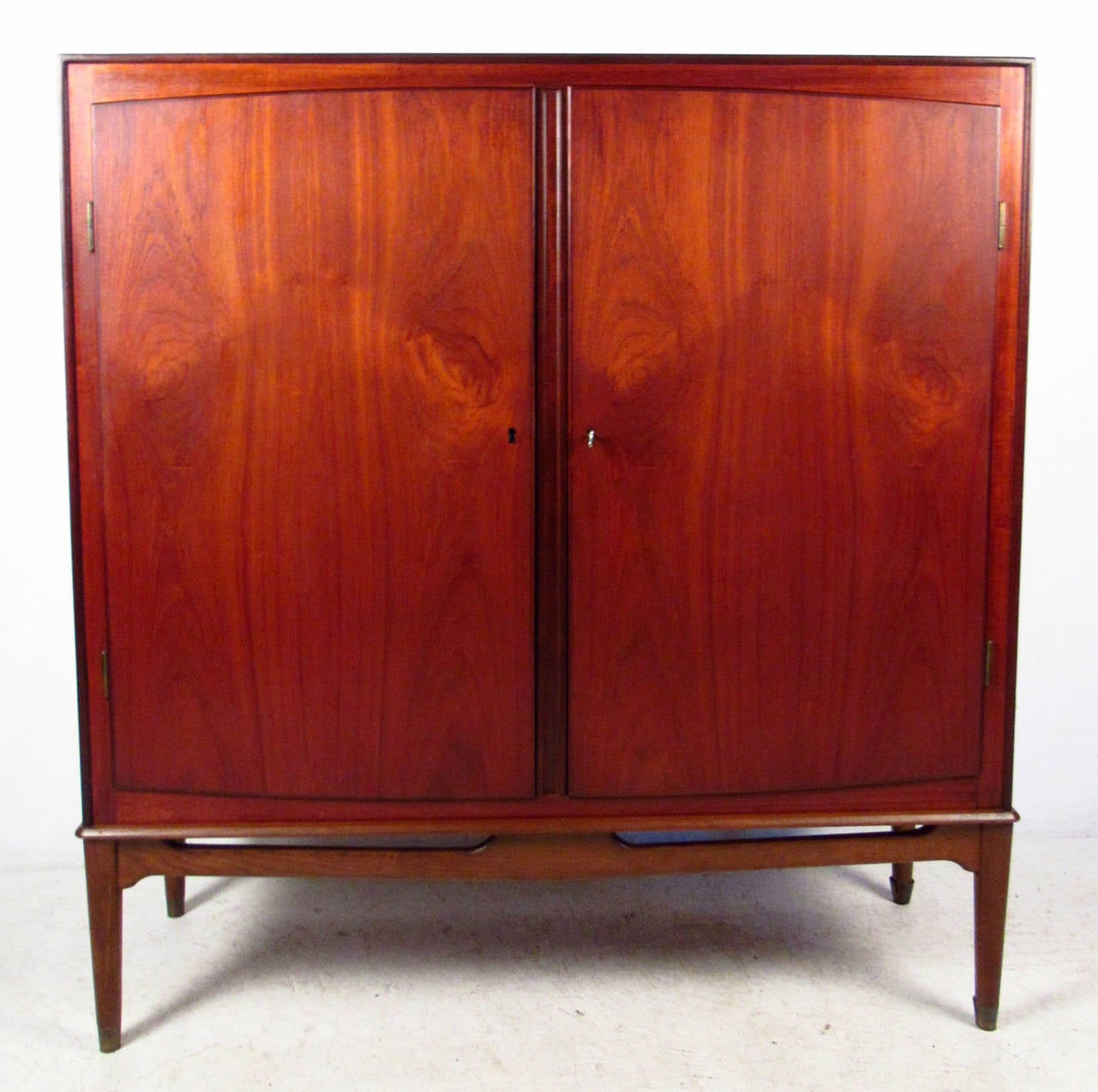 Vintage-modern tall teak cabinet, features beautifully sculpted base and two locking cabinet doors that reveal interior drawers and shelving. Stunning mid-century teak showcases Scandinavian modern design and quality craftsmanship. Ideal bedroom