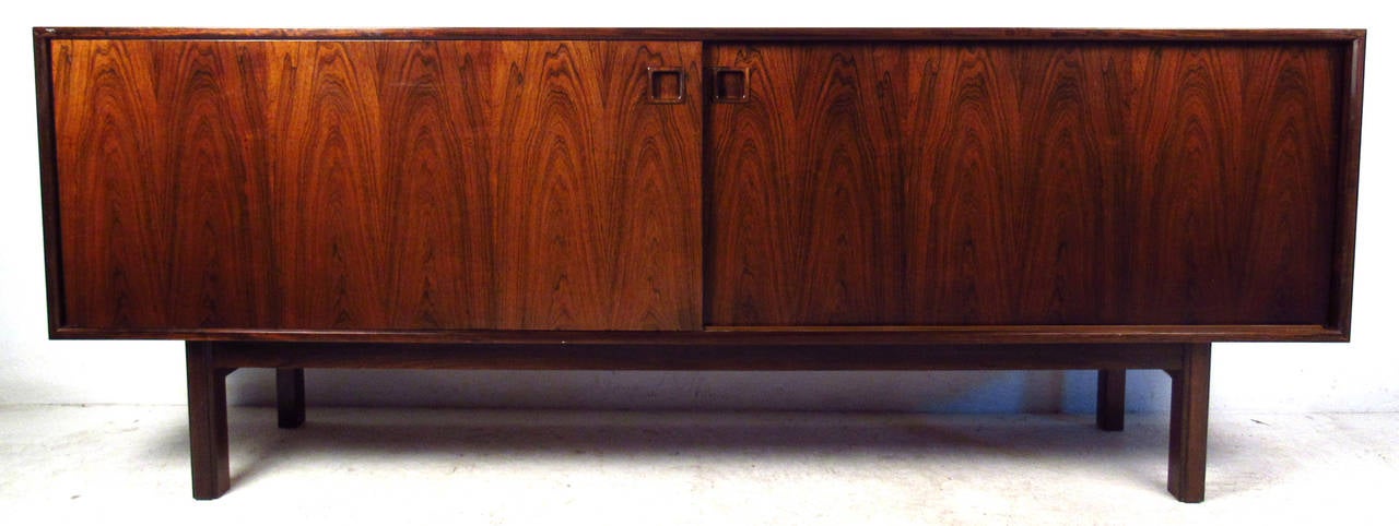 Vintage-modern Danish sideboard, model number 21 designed by Omann Jun Mobelfabrik, features two sliding doors revealing felt lined drawers and adjustable shelving.

Please confirm item location NY or NJ with dealer.