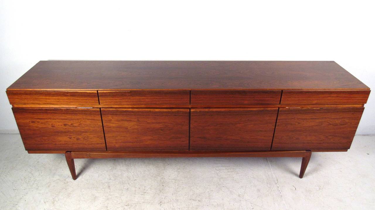 This Classic Mid-Century Danish design features wonderful straight lines, rich rosewood finish and plenty of storage for service or storage in any setting. Designed by Ib Kofod-Larsen for Faarup Møbelfabrik, this vintage piece boasts quality