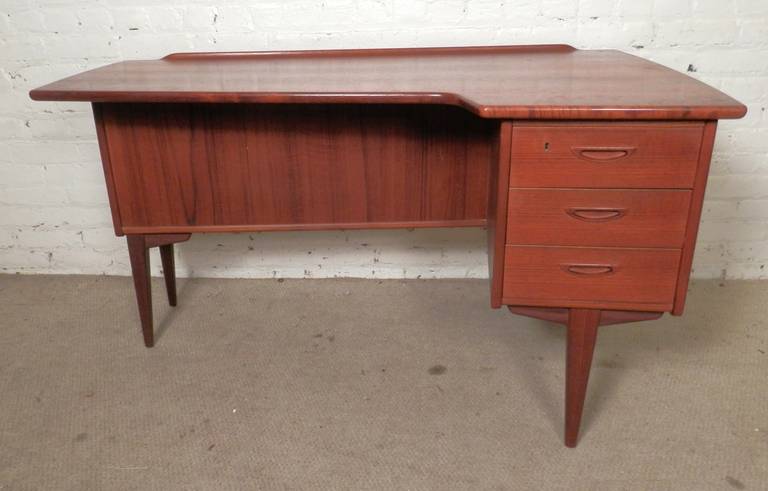 Stunning free-form top desk in the style of Arne Vodder, featuring a kidney shape top, tapered legs and upturned edge. Three front drawers with sculpted handles and a finished back with open cabinet and drop down storage compartment. Very unusual