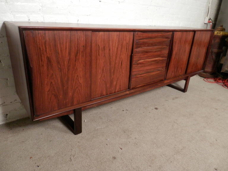 Mid-Century Modern Danish rosewood server with five sculpted drawers and two large cabinets each with an adjustable shelf. Appealing sled legs, adjustable shelving and rich rosewood grain.

(Please confirm item location - NY or NJ - with dealer).