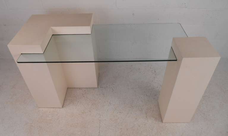 Contemporary style reception/writing desk featuring glass top supported by grasscloth covered forms. Unique modern design sets a simple yet stylish tone in any interior. Please confirm item location (NY or NJ) with dealer.