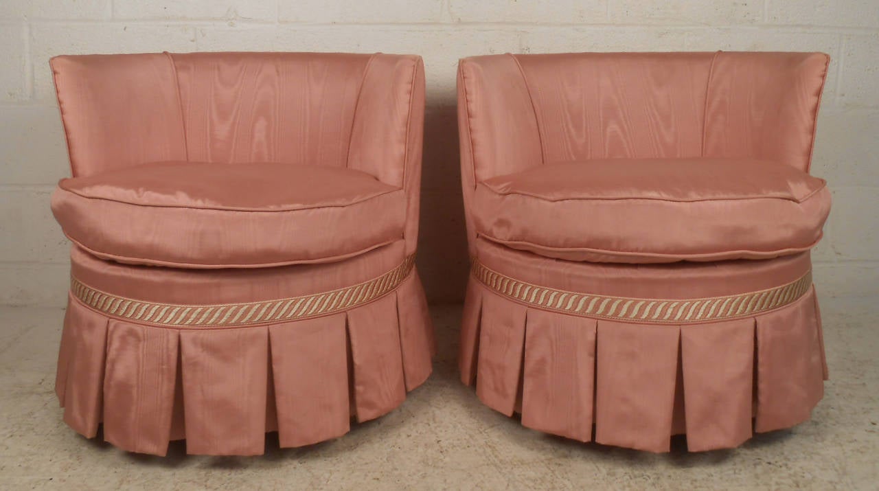 Two vintage-modern club chairs, featuring pink upholstery and wooden legs with brass wheels.

Please confirm item location NY or NJ with dealer.