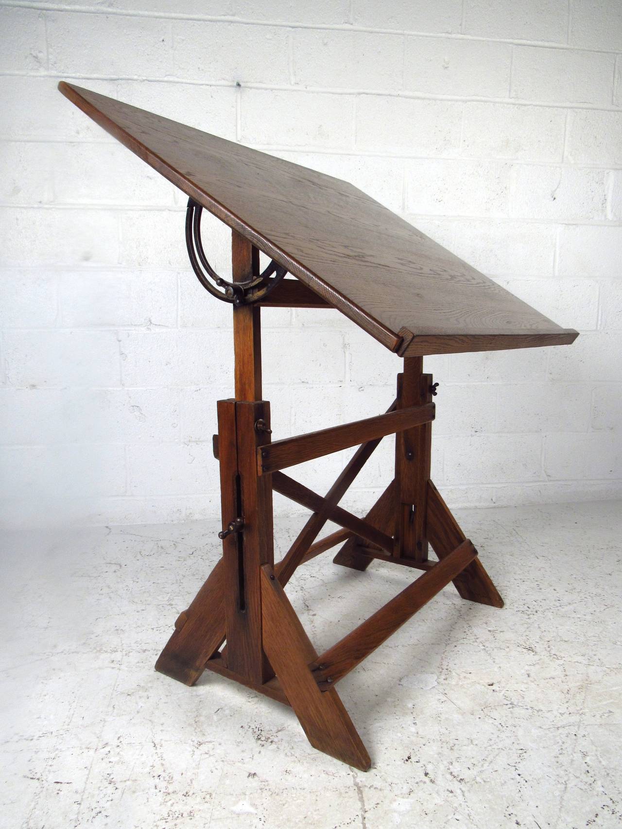 This circa 1940's drafting table is well constructed and easily adjusted for use as a practical workspace. Fantastic mix of oak and cast iron, this rustic drafting table makes a truly unique addition to any home, business, or office. Please confirm