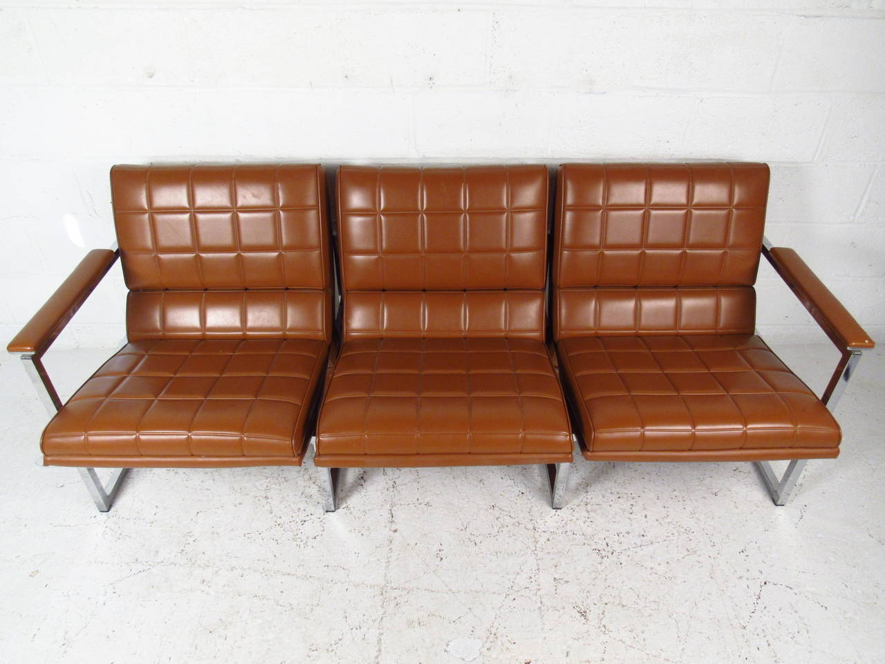 This beautiful vintage three-seat sofa features uniquely designed vinyl upholstery on a sturdy chrome frame. Padded armrests and waterfall style seat backs add to the charm of the piece, which makes a fantastic mid-century addition to any seating