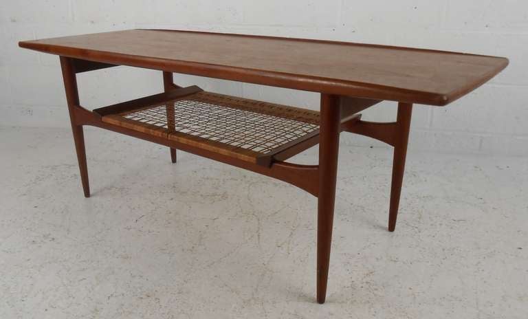 Danish modern table in teak with turned edges and lower cane shelf. Please confirm item location (NY or NJ) with dealer.