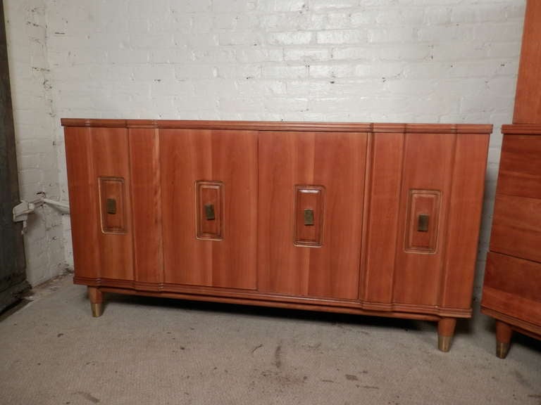 Mid-Century Modern set including long dresser, highboy chest and two nightstands. Lovely finish with brass accenting hardware and tapered feet with matching brass caps.

Measures: Dresser 60 W, 20 D, 32 H.
Chest 36 W, 21 D, 53 H
Nightstands 25