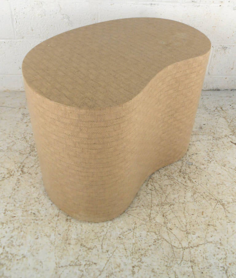 This unique coffee table is covered in a subtle woven canvas pattern and features a beautiful free-form kidney shape. Perfect for use as an end table or for display this wonderful end table makes a stylish midcentury accent to any room. Please