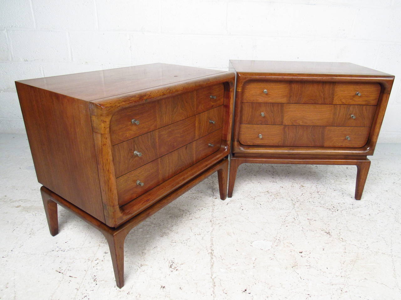 This unique pair of two drawer nightstands feature a mixed veneer pattern on the drawer fronts which compliments the unique pulls and tapered legs. This decorative pair of storage end tables are well suited to any setting, from bedroom nightstands