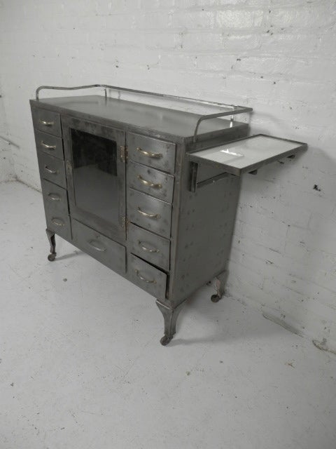 Fantastic doctors cabinet, complete with eleven drawers, glass door cabinet, and milk glass side shelf. All metal cabinet has been stripped down for a great industrial look.