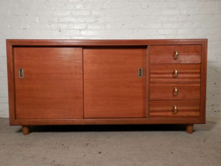 Vintage modern credenza with double sliding doors, brass ring pulls, and sculpted drawers. Doors reveal multiple sized drawers for storage. Perfect for use in a living room or bedroom.

(Please confirm item location - NY or NJ - with dealer).