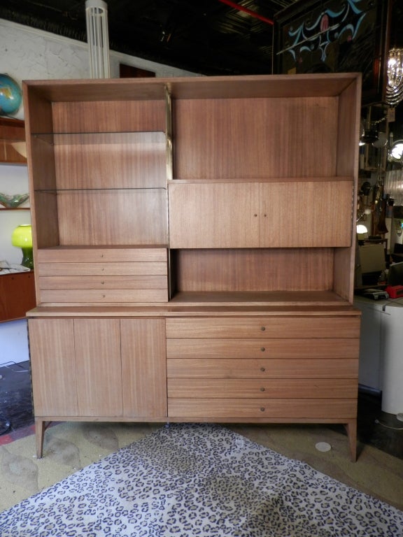 Outstanding break front/wall unit by mid-century designer Paul McCobb for the Calvin Group.
Classic McCobb brass hardware, glass shelves, five drawers to right side and triple folding door that opens to shelving.