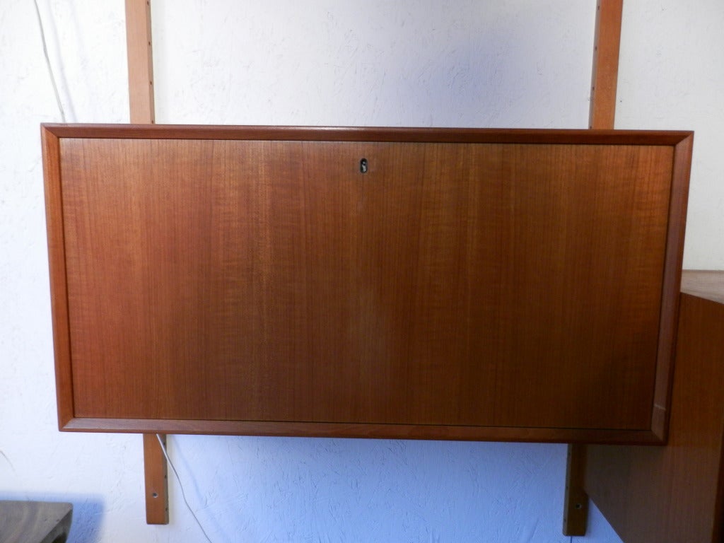This is a beautiful teak shelving and cabinet unit made in Denmark. Drop down desk, two door cabinet, sliding glass door cabinet, and three shelves, all of which can be rearranged easily and placed at any height.