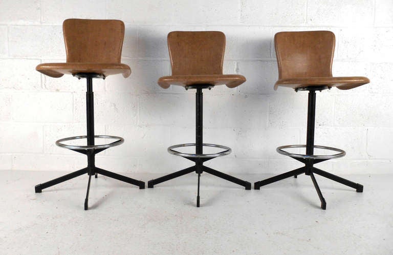 This set of three adjustable height fiberglass stools feature classic mid-century design, foot rest, and swivel motion. Manufactured by Hamilton Cosco Inc, this matching set of stools make a great addition to mid-century kitchen or bar. 
Please
