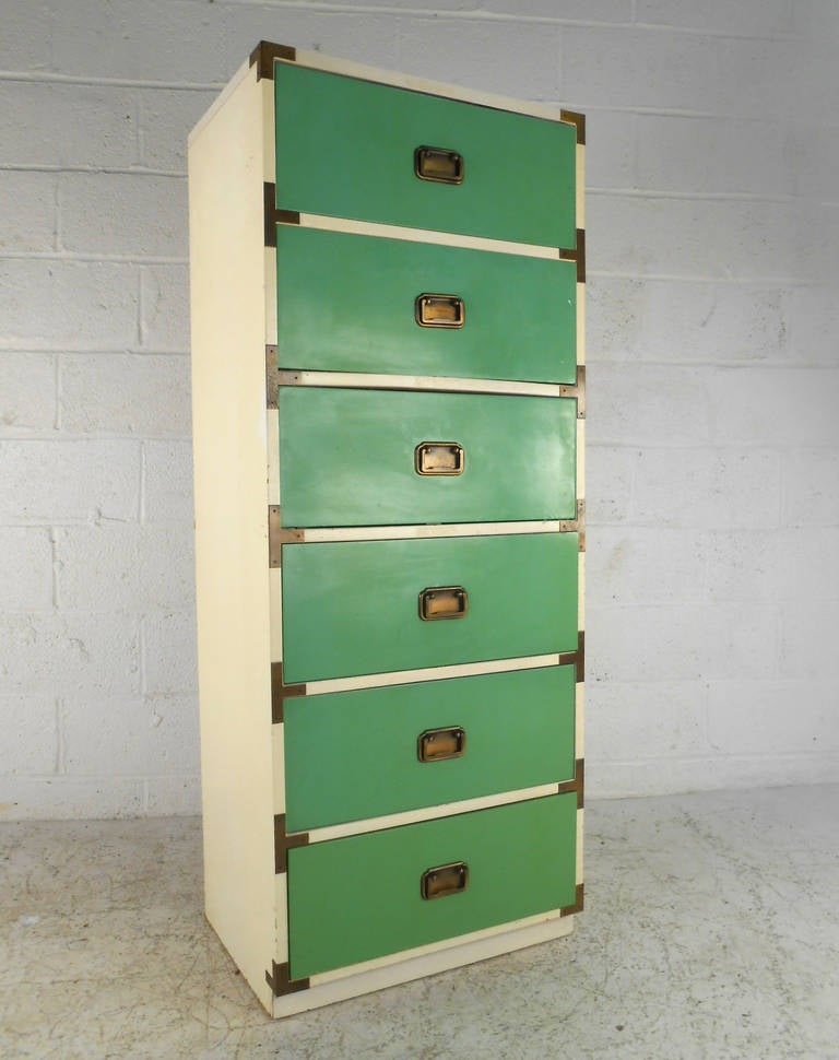 This unique green front campaign style chest of drawers features perfectly tarnished brass accents and a unique slender profile. It's almost lingerie chest style design combined with plentiful drawer space make this a unique, fun, and useful storage