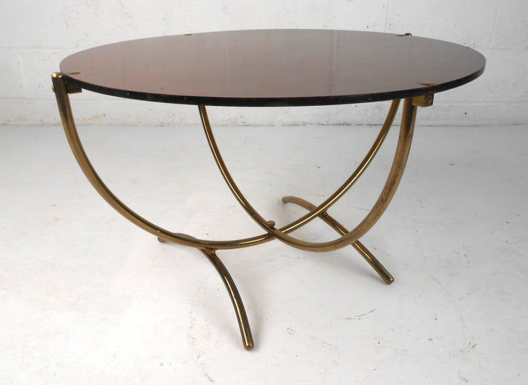 This simple yet decorative midcentury coffee table features a wonderful brass base with a wood grain finished top. Unique vintage table with interesting brass details, woodgrain laminate top. Please confirm item location (NY or NJ).