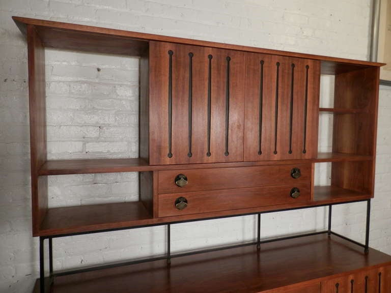 Mid-century modern walnut server with top cabinet. Accenting brass spade hardware, multiple cabinets, five drawers, sled style feet. Top rests on the bottom server/dresser and can be removed.

(Please confirm item location - NY or NJ - with dealer)