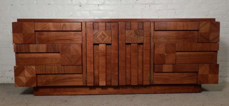 Paul Evans inspired walnut dresser with sculptural block mosaic patterns creating a mixture of grain patterns. Middle cabinet opens to three additional pull out drawers with three large drawers on wither side.

(Please confirm item location - NY