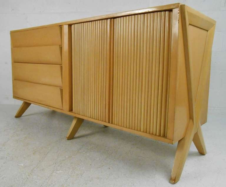 Bold midcentury design with flared legs, tambour doors, and eight drawers for storage. Please confirm item location (NY or NJ) with dealer.