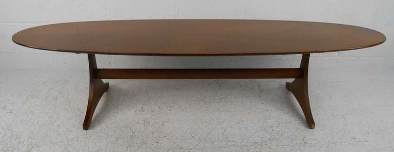 This unique Mid-Century Modern coffee table features a slender and stylish oval top with a rich vintage wood grain. Perfect cocktail table for home or business, please confirm item location (NY or NJ).