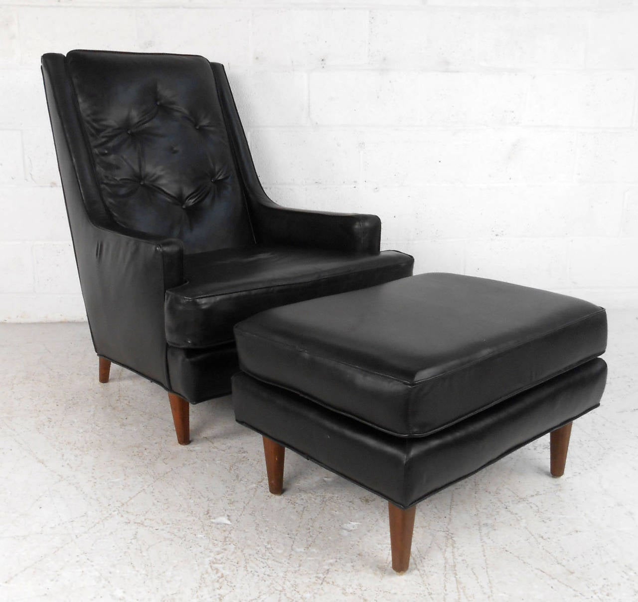 This matched lounge chair features unique tufted vinyl upholstery and tapered American walnut legs. Matching ottoman makes this an extremely comfortable retro addition to any seating arrangement. Please confirm item location (NY or NJ). Dimensions: