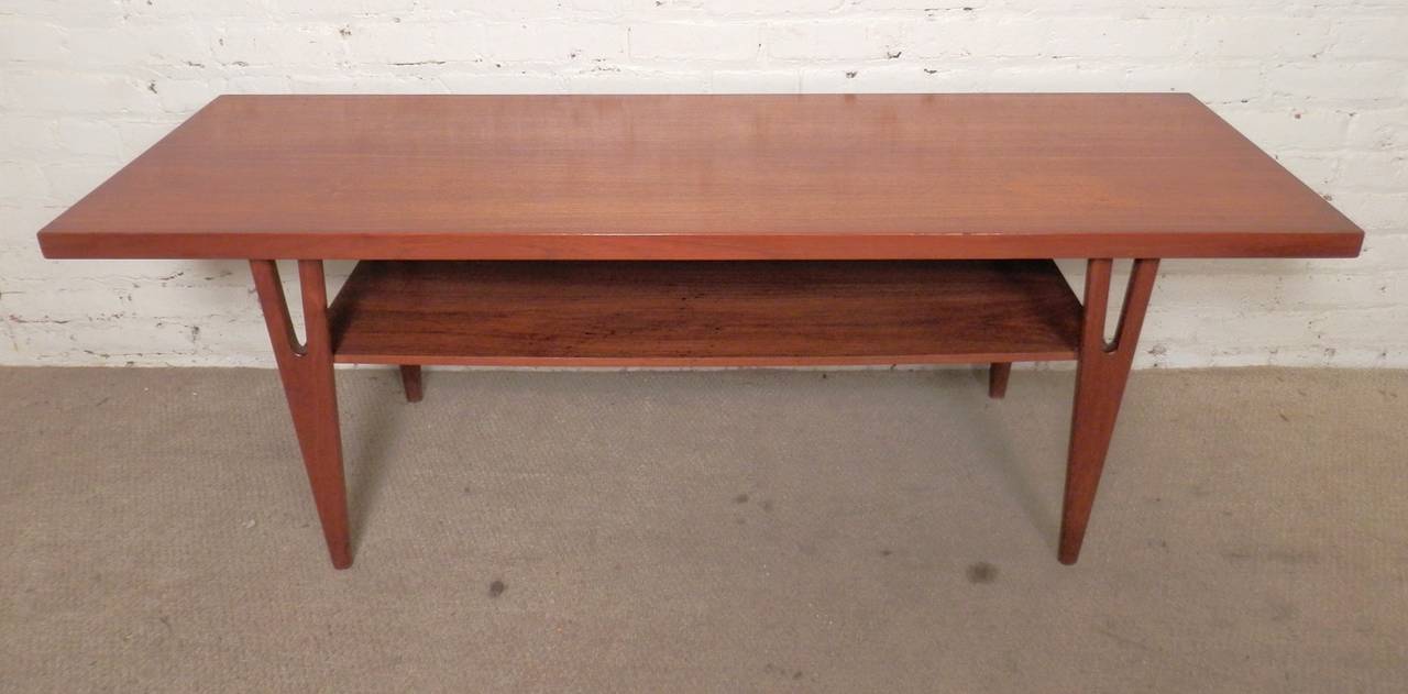 Mid-Century Modern sofa table with magazine shelf and sculpted legs. Teak grain throughout, Danish modern form.

(Please confirm item location - NY or NJ - with dealer).