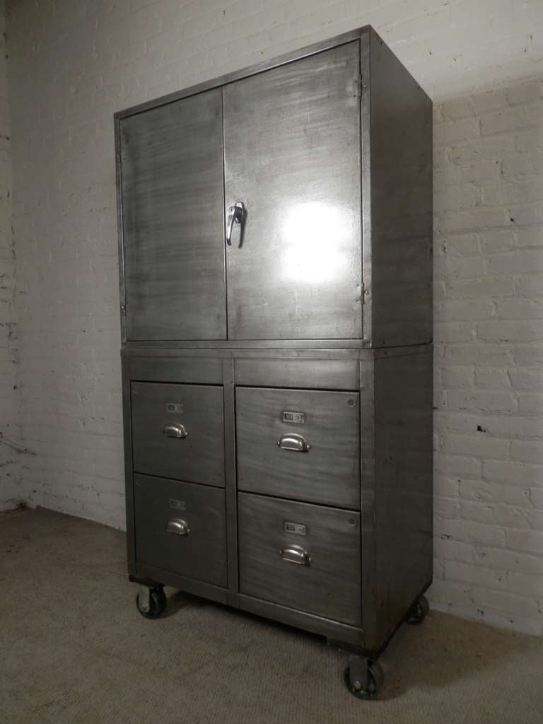 Massive two stack cabinet made of Industrial metal featuring two door open cabinet atop a rolling base with four large storage drawers. Two vintage units modified to make a sizable, functional piece, striped and lacquered for a fashionable machine
