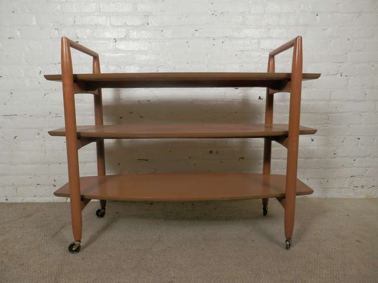 Vintage modern three-tiered serving cart on original casters. Nice walnut grain, bowed edge shelves, stylish modern lines from one of the best importer/makers of Mid-Century Modern furniture!

(Please confirm item location - NY or NJ - with