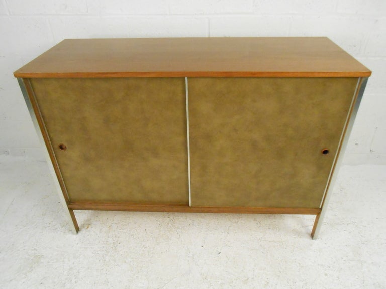 Walnut credenza featuring leatherette covered sliding drawers, adjustable shelves (2), metal leg trim and turned wood pulls.