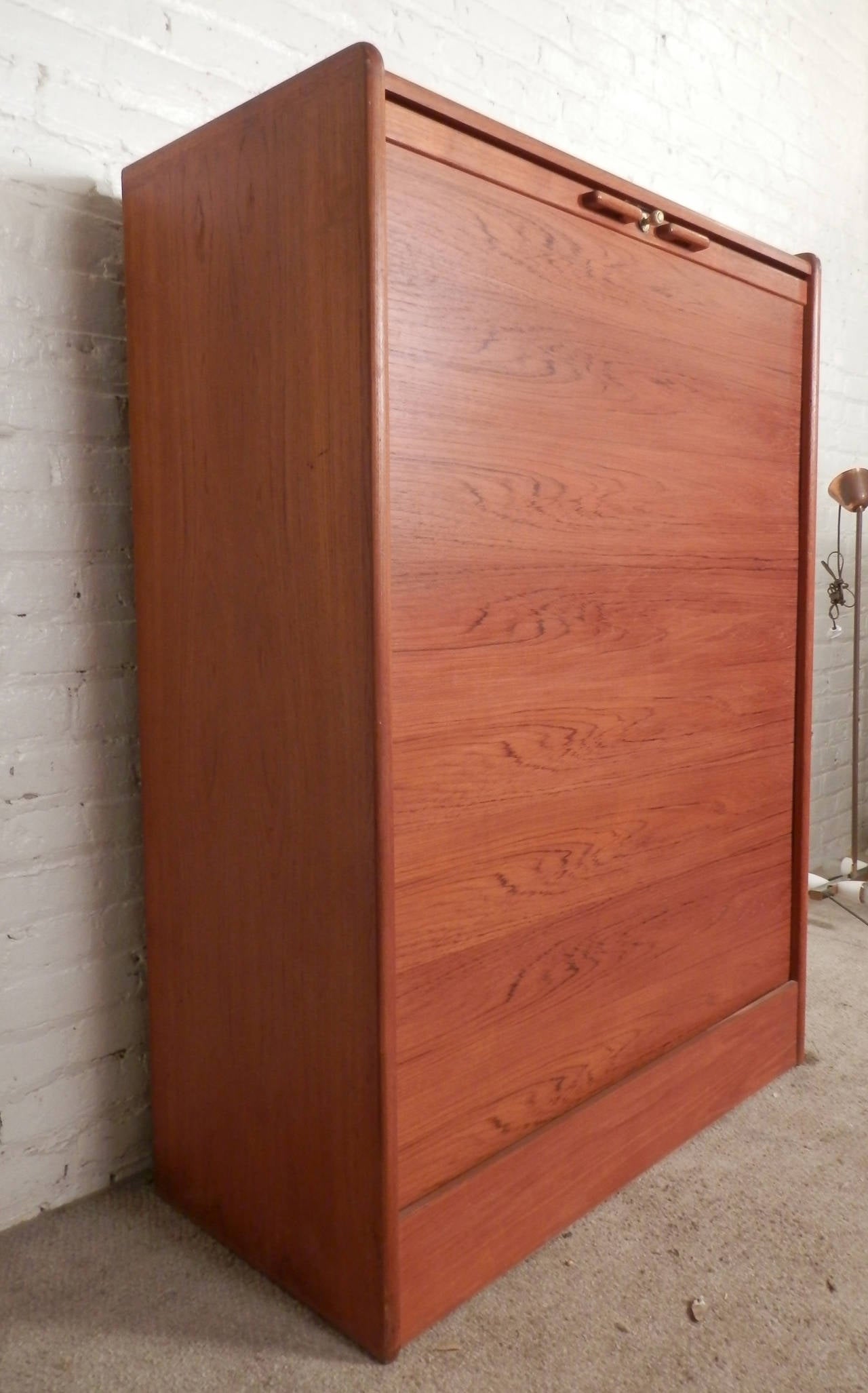 Mid-Century Modern dresser with vertical sliding door revealing three large drawers. Warm teak grain throughout, brass knob locks the tambour door in place. Works as a dresser or media closet.

(Please confirm item location - NY or NJ - with