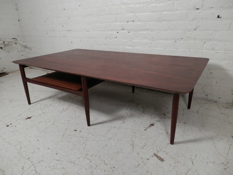 Mid-century modern walnut coffee table. Has a caned shelf that is in tact. Minor age appropriate wear.